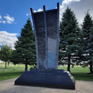 The Berlin Airlift Memorial is crafted from polished blue granite. It consists of a pedestal with engraved memorial information about the event which supports a curved multi-segment upright with laser engraved images. This memorial is on display at the National Museum of the United States Air Force in Dayton, Ohio.