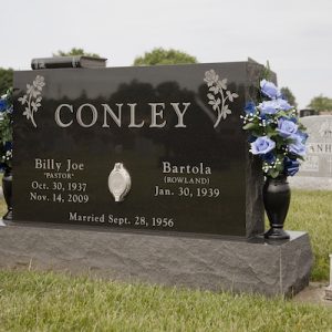 This Companion Upright honoring Conley monument is crafted from Asian Black granite and features flower urns and a floral design. The upright has a portrait embedded in the center. It is located at Byron Cemetery in Fairborn, Ohio. The memorial is suitable for use with traditional interment or cremation.