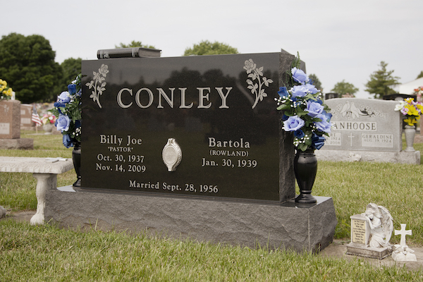 This Companion Upright honoring Conley monument is crafted from Asian Black granite and features flower urns and a floral design. The upright has a portrait embedded in the center. It is located at Byron Cemetery in Fairborn, Ohio. The memorial is suitable for use with traditional interment or cremation.