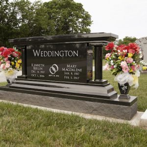 This Custom Companion Upright honoring Weddington, a large and wide companion upright monument is rendered in black granite and features twin columns and flower urns. There is an ornate cap stone installed over the top of the entire installation and it features engraved wedding rings. The memorial is suitable for use with traditional interment or cremation.