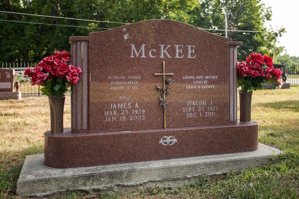 This Companion Upright honoring McKee is crafted from polished red granite and bronze and is flanked by two vases. It features a bronze sculpture with climbing roses. This memorial is suitable for use with traditional interment or cremation.