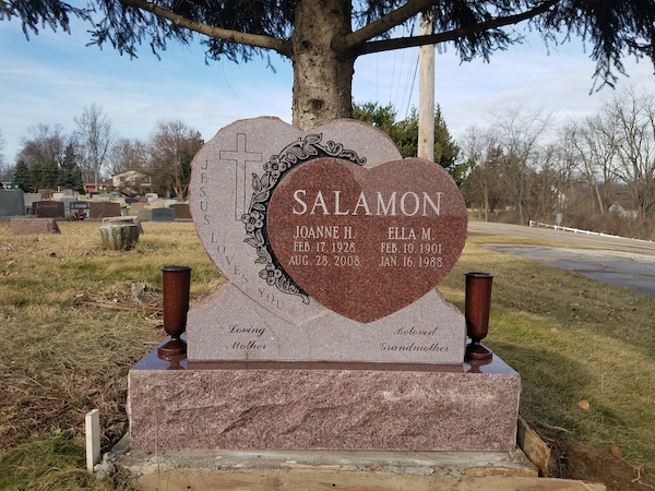 This Custom Companion Upright with Double Heart is rendered in India red granite and features an engraved cross and floral scrollwork. Contrast is provided with sawn finish on one heart and polished finish on the second heart. Located at Mt. Zion Park in Beavercreek, Ohio. This memorial is suitable for use with traditional interment or cremation.