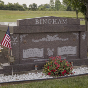 The Bingham Family Mausoleum is crafted from red granite. It features engravings of an eagle with floral accents, the US Air Force logo, and an angel with a cross. This memorial is suitable for traditional interment or cremation.