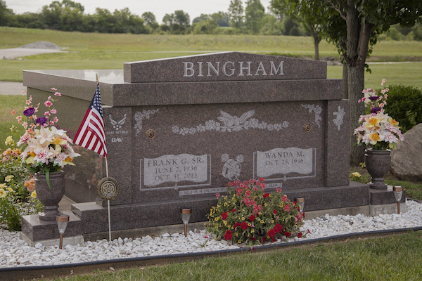 The Bingham Family Mausoleum is crafted from red granite. It features engravings of an eagle with floral accents, the US Air Force logo, and an angel with a cross. This memorial is suitable for traditional interment or cremation.