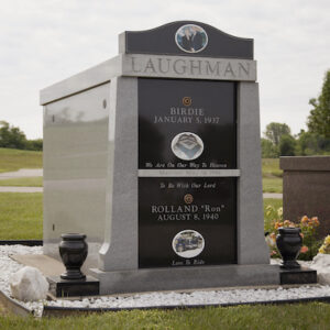 This Laughman Family Mausoleum is a custom companion estate mausoleum crafted out of gray and black granite, with color portraits, a cap stone, flower urns installed at Byron Cemetery in Fairborn, Ohio. It is appropriate for use with traditional interment or cremation.
