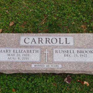 This Companion Bevel Marker honoring Carroll is crafted from pink granite and features an engraved cross. It is suitable for use with traditional interment or cremation.