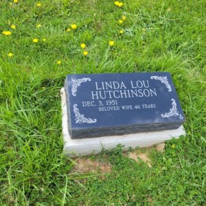 This Single Bevel Marker honoring Hutchinson is crafted from polished black granite. It features engraved scrollwork on all four corners of the stone. This memorial is suitable for use with traditional interment or cremation.