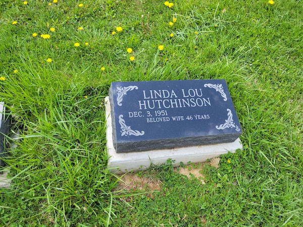 This Single Bevel Marker honoring Hutchinson is crafted from polished black granite. It features engraved scrollwork on all four corners of the stone. This memorial is suitable for use with traditional interment or cremation.