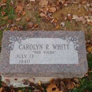 This Single Bevel Marker honoring Whitt is crafted from red granite. It features engravings of roses in the top corners of the stone. This memorial is suitable for use with cremation or traditional interment.
