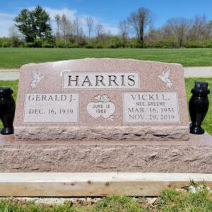 This Companion Slant on a Base honoring Harris is crafted from pink granite and is flanked by two vases. It features engravings of doves and joined hearts. This memorial is appropriate for use with cremation or traditional interment.