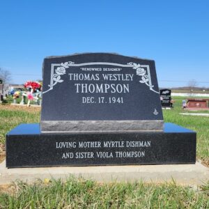This Single Slant Marker on a Base honoring Thompson is crafted from polished black granite. It features engraved floral themed scrollwork along with the memorial information. This memorial is suitable for cremation or traditional interment.