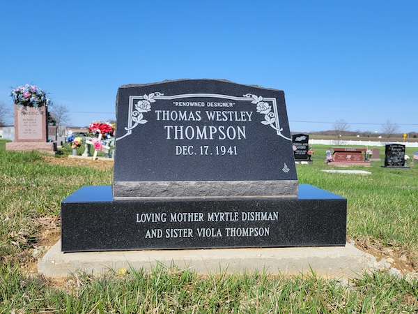 This Single Slant Marker on a Base honoring Thompson is crafted from polished black granite. It features engraved floral themed scrollwork along with the memorial information. This memorial is suitable for cremation or traditional interment.