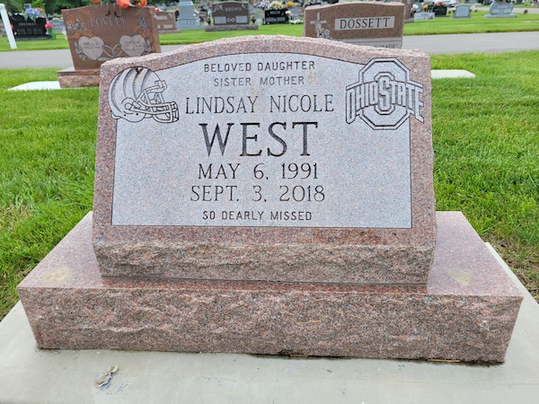 This Single Slant Marker on a Base with Ohio State Logo is crafted from red granite. It features engravings of the Ohio State Logo and a Cincinnati Bengals football helmet. This memorial is suitable for use with cremation or traditional interment.