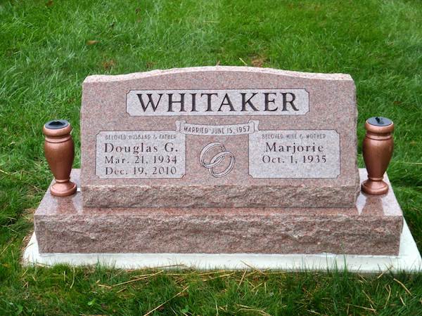 This Companion Slant Marker honoring Whitaker is crafted from red granite and is flanked with two vases. It features a carving of intertwined rings. This memorial is suitable for use with cremation or traditional interment.