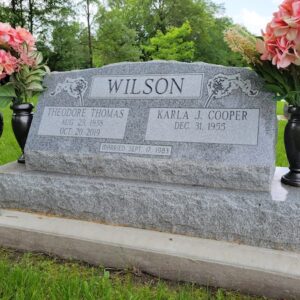 This Companion Slant on a Base honoring Wilson is crafted from gray granite and is flanked by two vases. It features floral themed engravings along with the memorial information. This monument is appropriate for use with cremation or traditional interment.