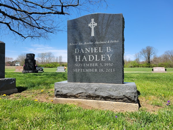 This Single Upright honoring Hadley is crafted from blue granite. It features an engraving of a Celtic cross and is suitable for use with traditional interment or cremation.