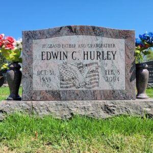 This Single Upright honoring Hurley is a monument with a wide stone, a custom engraved eagle and American flag, with flower urns, in red granite. It is appropriate for use with cremation or traditional interment.
