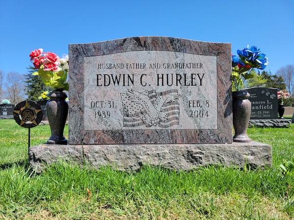 This Single Upright honoring Hurley is a monument with a wide stone, a custom engraved eagle and American flag, with flower urns, in red granite. It is appropriate for use with cremation or traditional interment.