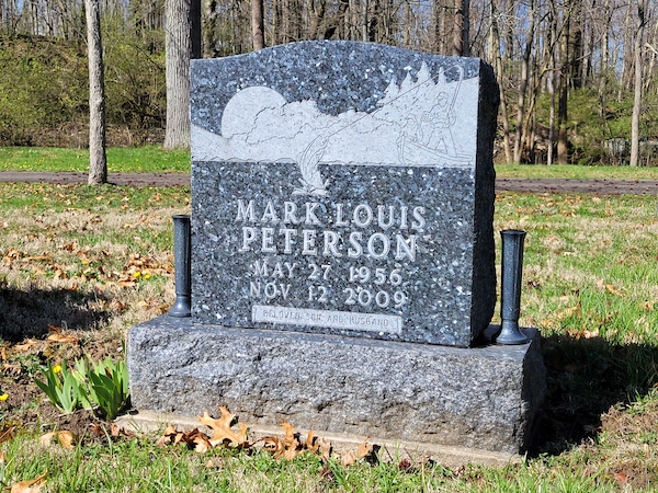 This Single Upright with Fisherman is a monument with vases, crafted from Swedish Blue Pearl Granite and has an engraving of a fisherman. It is located at Sugar Grove Cemetery in Wilmington, Ohio. The memorial is suitable for use with traditional interment or cremation.