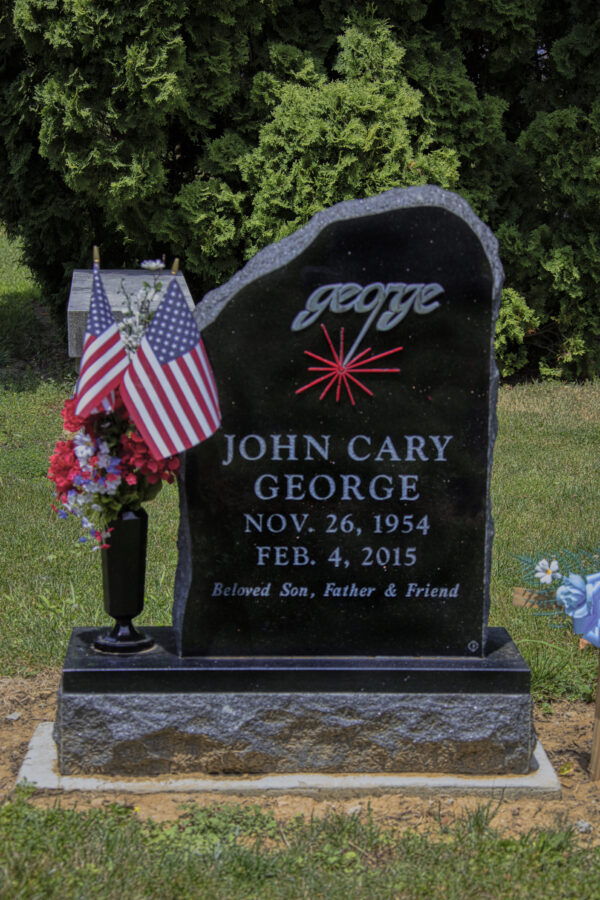 This Custom Single Upright with Vase is crafted from polished black granite and features a stylized version of the name "George" with a red colored laser zap. This monument is suitable for use with cremation or traditional interment.