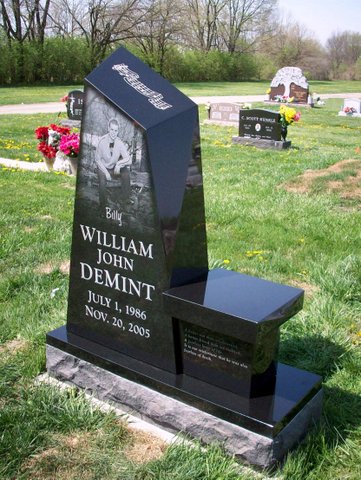 This Custom Single Upright with Bench memorial is crafted from an irregular polished black granite stone and features a photo realistic laser engraving of the decedent. This memorial is appropriate for use with traditional interment or cremation.