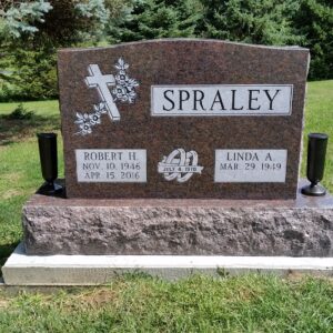 This Companion Upright honoring Spraley is crafted from brown granite and is flanked by two vases. It features an engraved cross with flowers and entangled rings. This memorial is suitable for use with traditional interment or cremation.