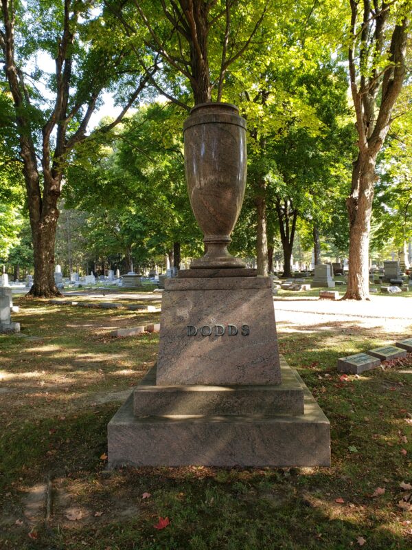 The Historic Dodds Family Estate Memorial is crafted from polished red granite and is composed of a stepped base and a large sculpted vase atop the pedestal. It features the Dodds family name in bronze prominently on one side of the pedestal. This monument is appropriate for use with cremation or traditional interment.