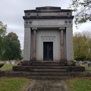 The Historic Lowry Mausoleum is crafted from gray and red veined granite in the style of a traditional family vault building. The monument features columns carved from red veined granite, art deco style metal doors, and a carved lentel section over the door. This is a piece of art in addition to a family memorial.