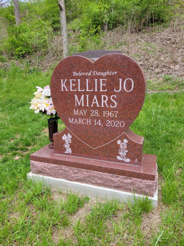 This Custom Single Upright with Mickey Mouse is crafted from polished red granite in the shape of a heart and flanked by a vase. The memorial features carved images of Mickey Mouse and Minnie Mouse. It is suitable for use with traditional interment or cremation.
