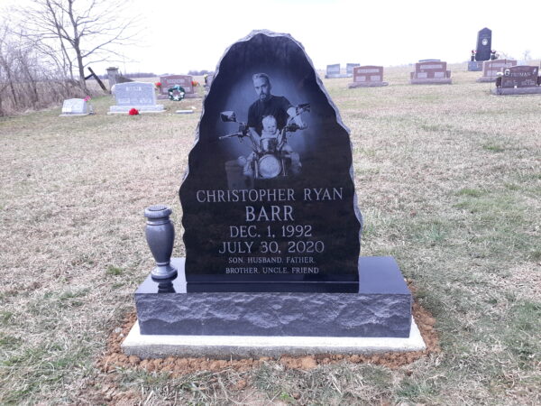 This Custom Single Upright with Motorcycle rendered with laser engraving on polished black granite. The shape of the stone has been customized to accommodate the decedent's photo realistic image riding his bike. This memorial is suitable for cremation or traditional interment.