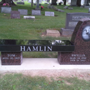 This Custom Companion Bench in Brown and Black Granite uses polished black granite as the bench seat and brown granite for the supports. One of the supports is a large irregular shape and features a laser engraved photo realistic image of the decedents. This memorial is appropriate for use with cremation or traditional interment.