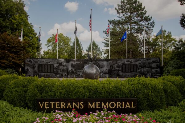 The Middletown Area Veterans Memorial is a large installation crafted from polished black granite. It features a large curved wall with laser engraved images of different scenes from military service, equipment, and engagements. In the forefront, a large globe is centered on the wall and an eagle sculpture is perched atop the globe. You can see this memorial in Middletown, Ohio.