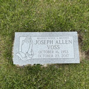 This single flush marker in gray granite features a carving of hands in prayer. Wether one opts for traditional interment or cremation, this memorial will suit.