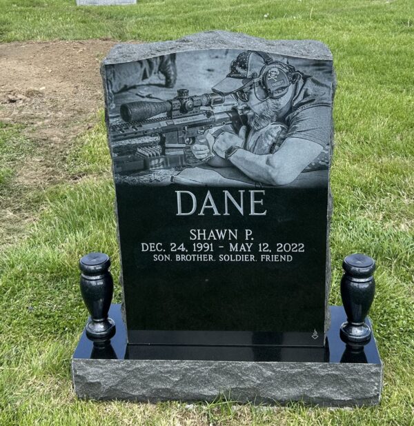 This Custom Laser Single Upright memorial crafted in black, polished granite features a laser engraved image of the deceased aiming a rifle. This marker is appropriate for cremation or traditional interment.