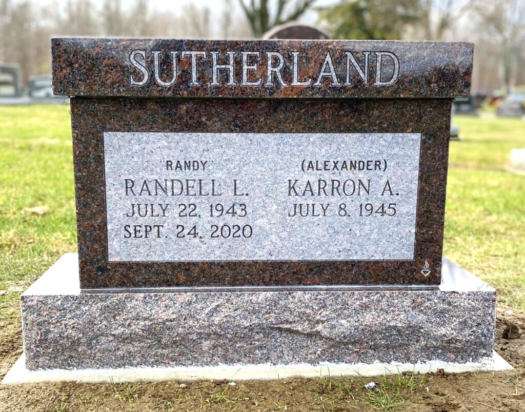 This upright companion memorial honors the Sutherlands and is crafted from Carnelian Mahogany granite. The memorial features a simple form with a flat top and is suitable for honoring those who have been cremated.