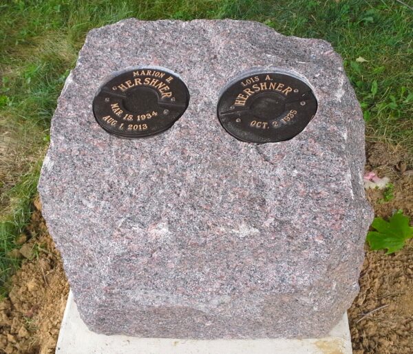 This creative and natural memorial is crafted from a rustic mahogany granite with separate bronze niches for loved one's cremains. While simple, this design integrates well into a natural setting and is striking in its appearance.